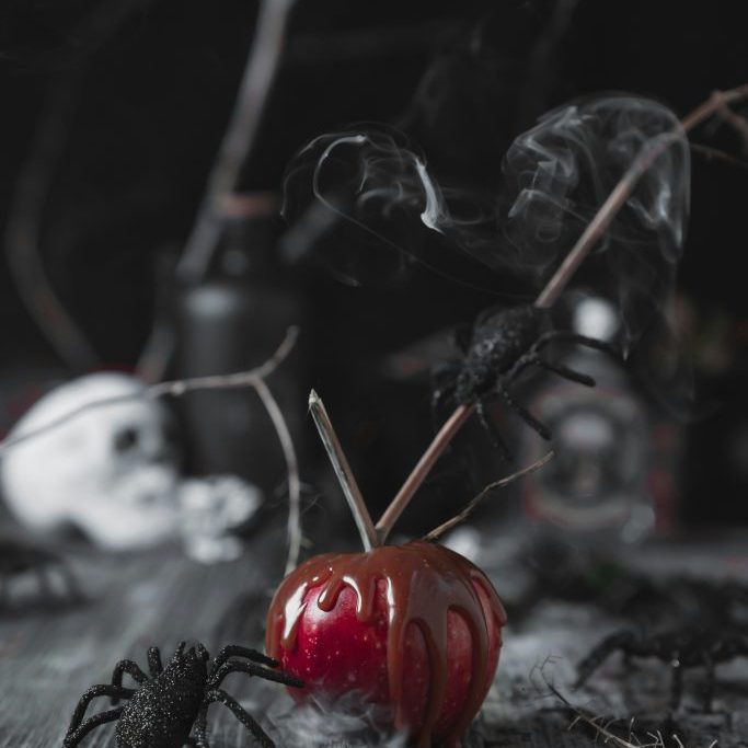 A reflective orange pumpkin sits centered in a spooky backdrop, surrounded by encroaching black spiders and spiderwebs.